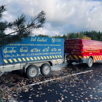 Autosõidu kaubik ja haagis sügislehtedega kaetud platsil